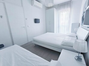 A modern hotel room with a bed, bedside table, lamp, and a large mirror. - Apartment With Balcony and Pool Access (Jesolo)