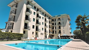 Hotel de diversos pisos amb piscina, balcons i un cel blau clar.