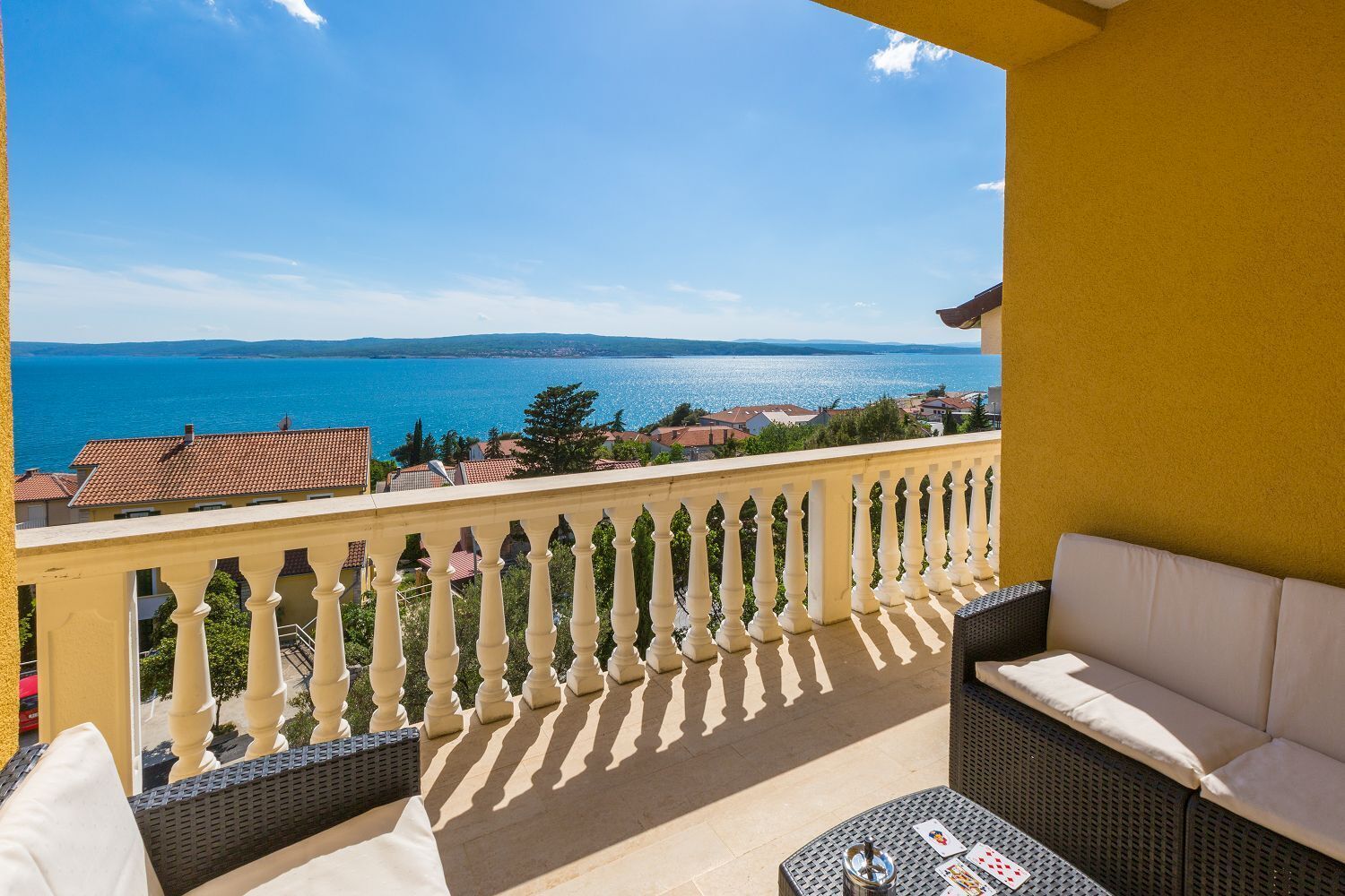 A balcony with a view of the sea, a sofa, and a table.