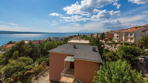 Un quartier résidentiel situé sur la côte, offrant une vue sur la mer, avec des maisons aux toits recouverts de tuiles rouges et un petit bâtiment doté d’un balcon.