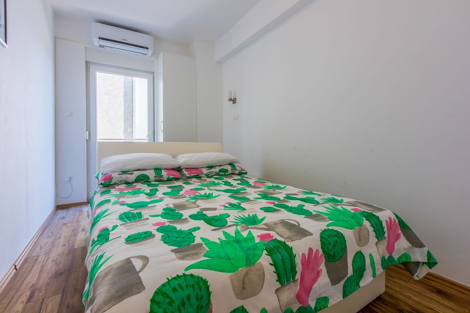 Ein Schlafzimmer mit Bett, Fenster und Klimaanlage.