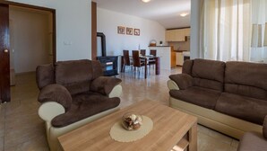 A living room with two brown sofas, a wooden coffee table, and a dining area with chairs and a table in the background. - Special apartment with pool, barbecue area, washing machine, sea view, air conditioning (Grižane)