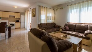 A modern living room with a sofa set, a dining table, and a kitchen area with cabinets and appliances. - Special apartment with pool, barbecue area, washing machine, sea view, air conditioning (Grižane)