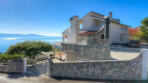 Una casa costera con un muro de piedra, un balcón y vista al mar.