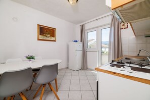 Eine kompakte Küche mit Gasherd, Kühlschrank und einem Essbereich mit Tisch und Stühlen.