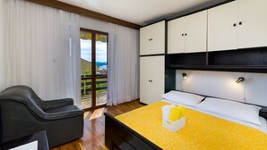 Ein Schlafzimmer mit Bett, Stuhl und Blick ins Freie.