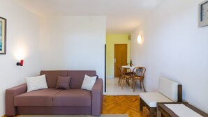 Ein Wohnzimmer mit einer Couch, einem Esstisch mit Stühlen und einem kleinen Holztisch.
