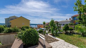 Ein Küstenwohngebiet mit Häusern, einem gepflasterten Weg und Blick auf das Meer.