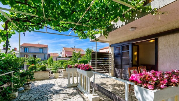 Ein Innenhof mit Steinboden, Kübelpflanzen und Sitzgelegenheiten im Freien.