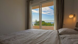 Une chambre à coucher avec un lit, une fenêtre avec des rideaux et une vue sur l’extérieur.