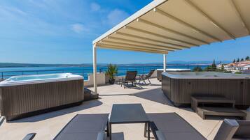 Une terrasse sur le toit avec un jacuzzi, un espace salon et une vue sur la mer.
