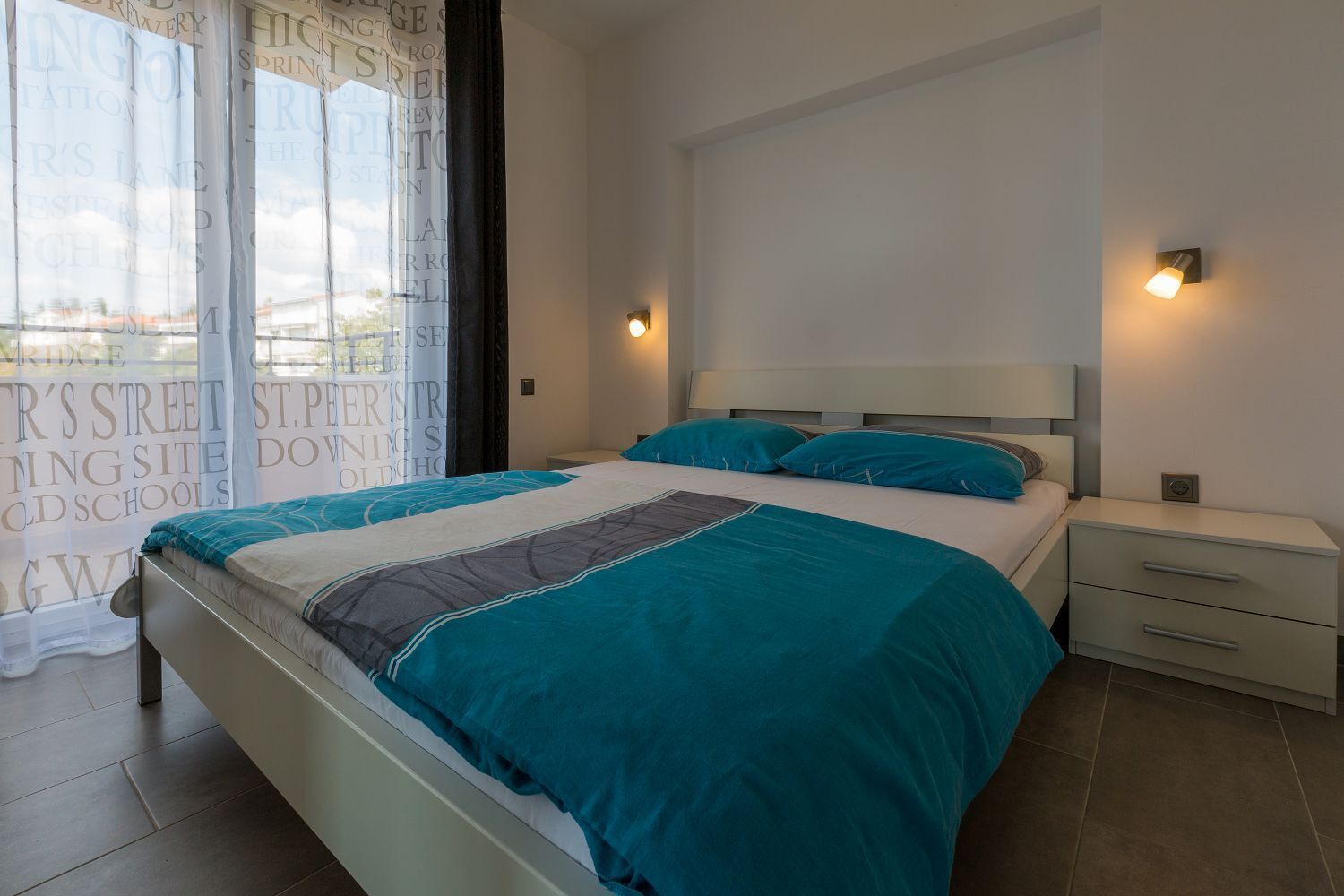 Ein Schlafzimmer mit Bett, Nachttisch und einem Fenster mit Vorhängen.