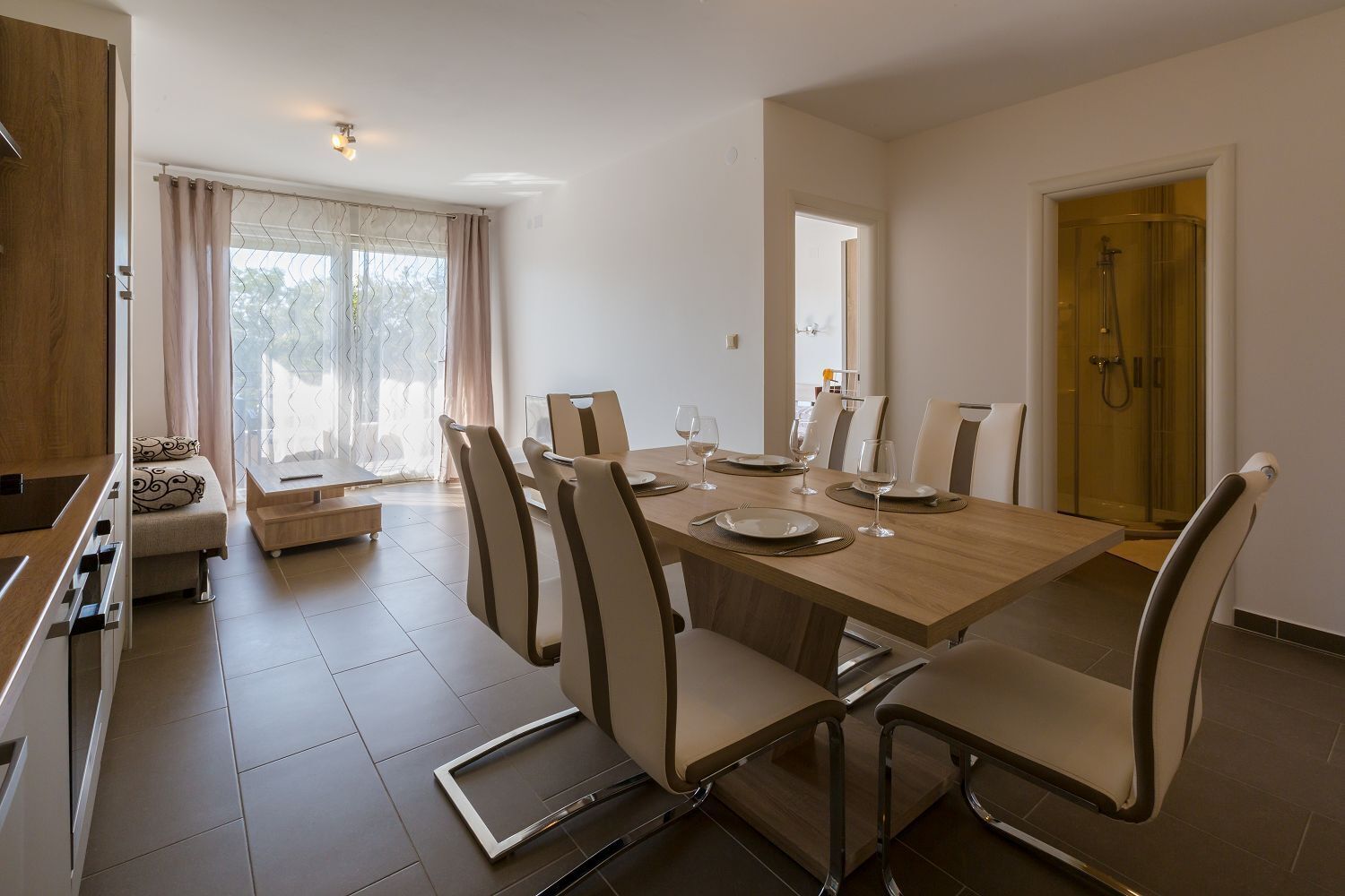 A modern dining area with a wooden table set for six, surrounded by six chairs.