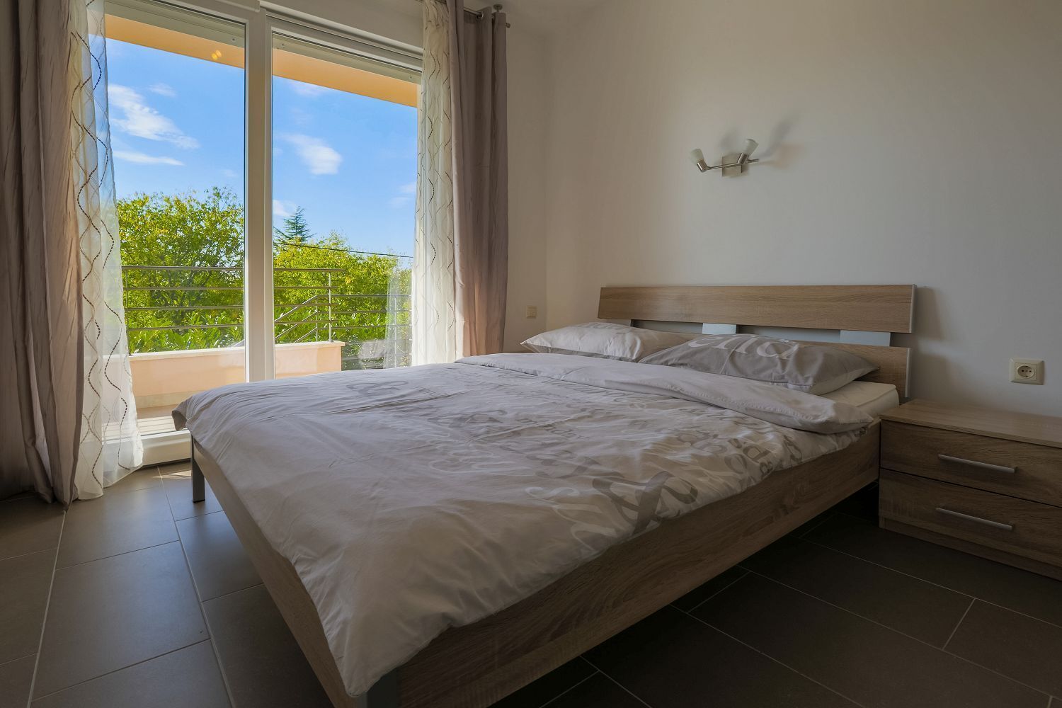 Ein Schlafzimmer mit einem großen Bett, einem Holzkopfstück, einem Nachttisch und einer Wandleuchte.