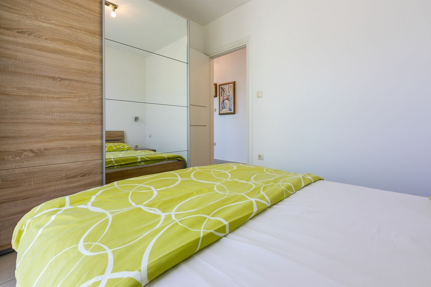 Ein Schlafzimmer mit einem Bett, einem Holzschrank und einem Spiegel.