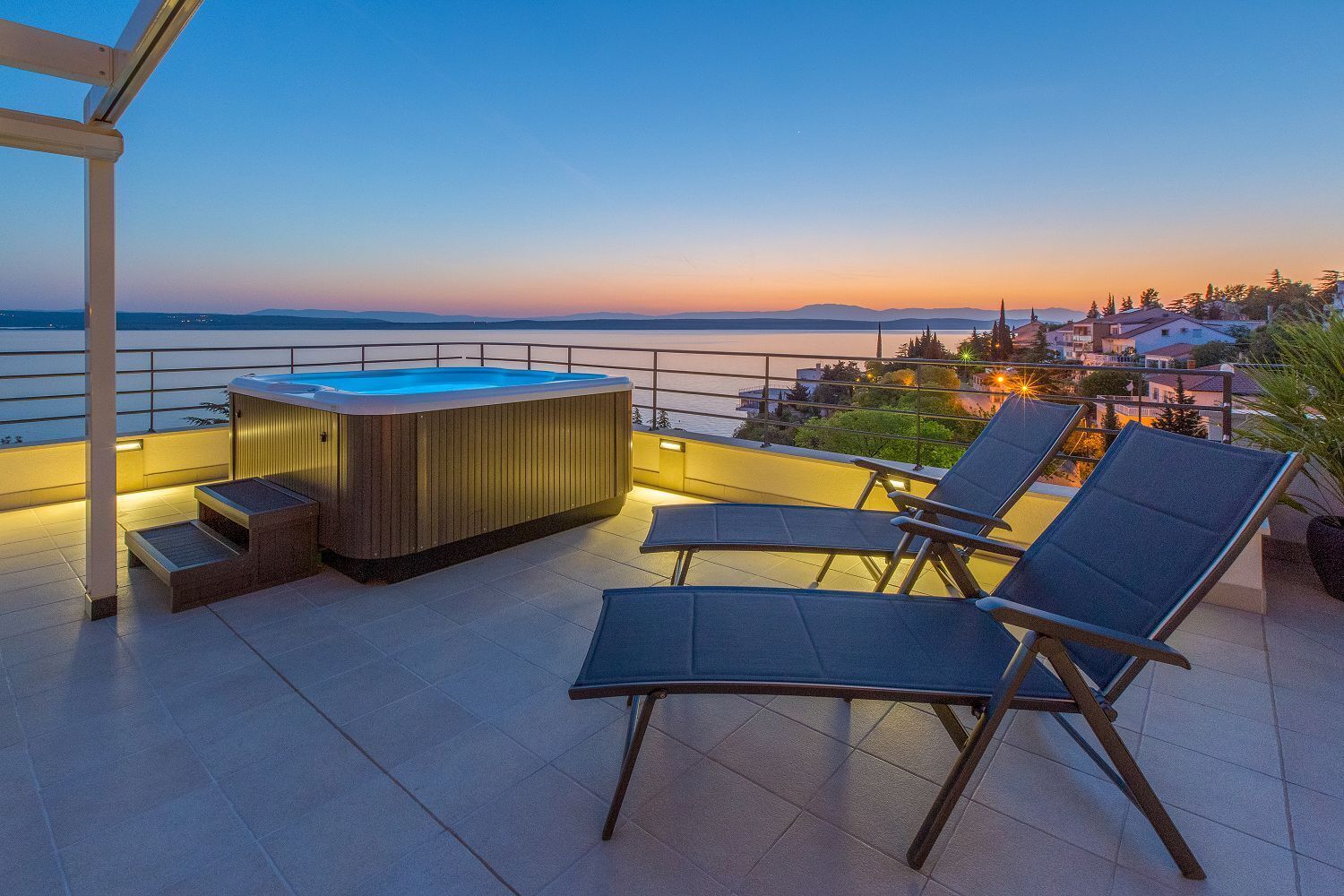 Une terrasse sur le toit avec un jacuzzi, des chaises longues et une vue sur la ville au coucher du soleil.