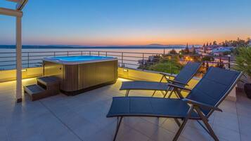 Une terrasse sur le toit avec un jacuzzi, des chaises longues et une vue sur la ville au coucher du soleil.