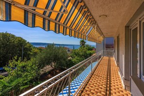 Un balcone con vista sul mare, un pavimento piastrellato e un tendone a righe.