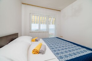 A hotel room with a bed, two rolled towels, a patterned bedspread, and a window with curtains. - Large apartment just 400 metres from the beach with sea view, barbecue area, WiFi, air conditioning (Crikvenica)