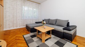 Un soggiorno moderno con un divano grigio, un tavolino in legno e un tappeto a scacchi.