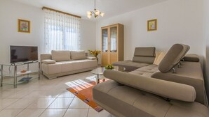Een moderne woonkamer met een bank, een televisie en een kast.