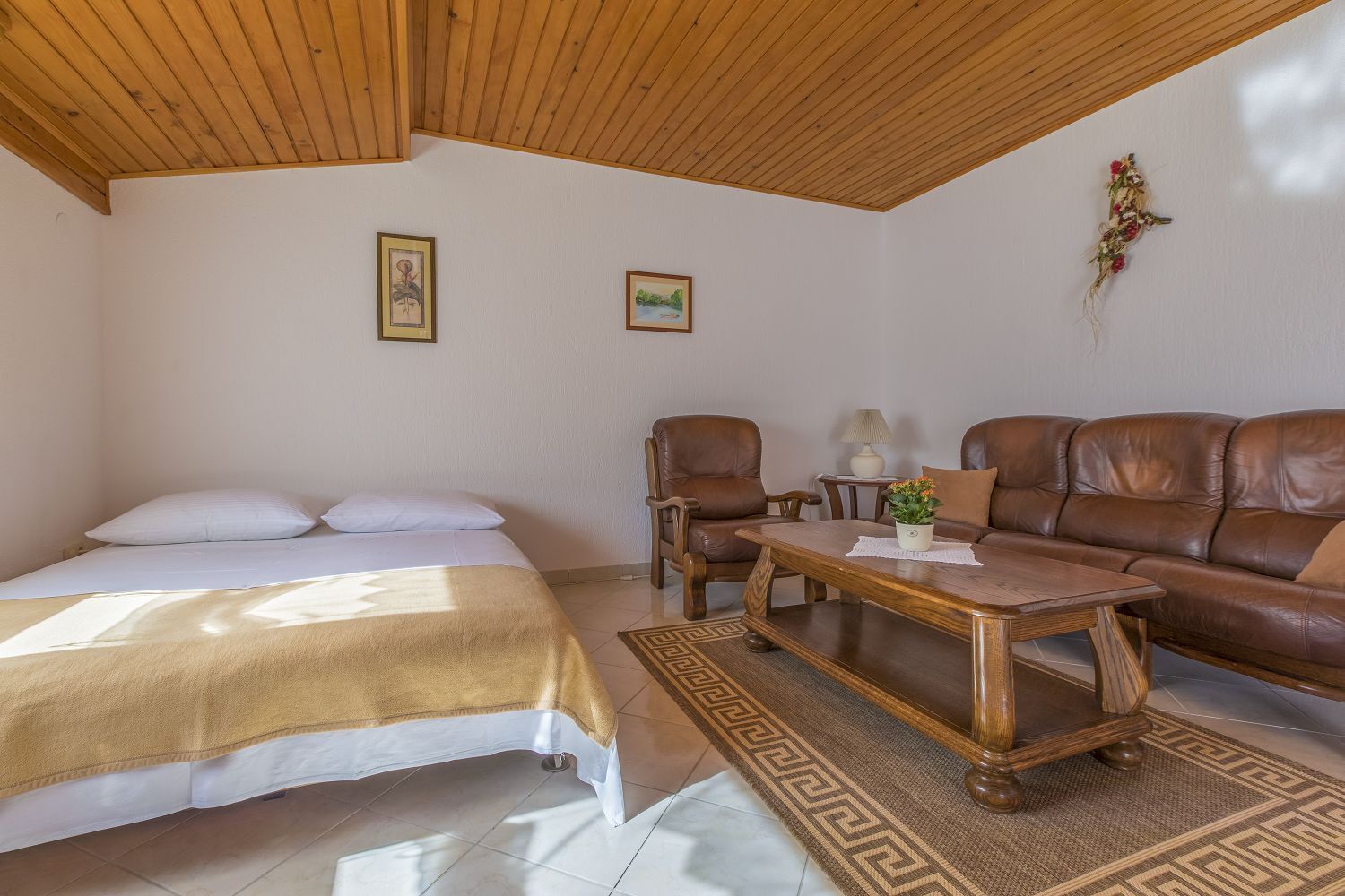 Ein Zimmer mit einem Bett, einem Schlafsofa, zwei Stühlen, einem Couchtisch und einem kleinen Tisch mit einer Lampe.