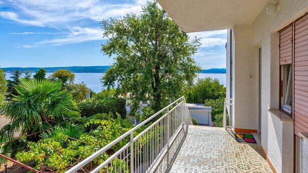A balcony with a tiled floor, a metal railing, and a view of a body of water and greenery. - Rustic apartment just 100 metres from the beach with sea view, balcony, terrace, air conditioning (Crikvenica)