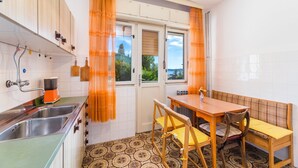 A compact kitchen with a sink, stove, and dining area. - Rustic apartment just 100 metres from the beach with sea view, balcony, terrace, air conditioning (Crikvenica)
