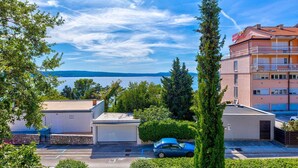 A hotel with a view of the sea, a parking area, and surrounding greenery. - Rustic apartment just 100 metres from the beach with sea view, balcony, terrace, air conditioning (Crikvenica)