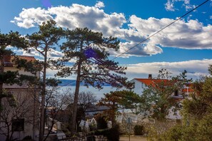A coastal residential area with houses, a stone wall, and a view of the sea. - Dog-friendly studio apartment just 250 metres from the beach with sea views (Novi Vinodolski)