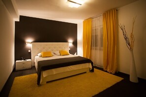 Una camera da letto moderna con un letto grande, un comodino e un vaso con rami.