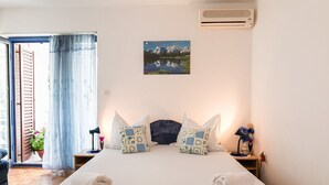 A bedroom with a bed, pillows, a nightstand, a lamp, and a painting on the wall. - Dog-friendly studio apartment just 580 metres from the beach with parking space (Selce)