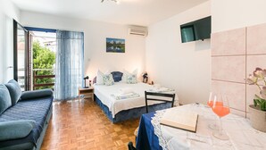 A bedroom with a bed, a small table with a book and a glass of orange juice, a sofa, and a window with curtains. - Dog-friendly studio apartment just 580 metres from the beach with parking space (Selce)