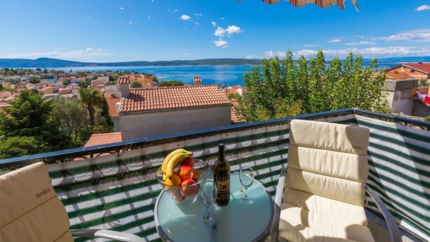 A balcony with a table set for two, a bottle of wine, and a bowl of fruit. - Bright apartment just 400 metres from the beach with stunning sea views and two bikes (Selce)
