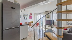 A modern kitchen with a stainless steel refrigerator, a dining area with a table and chairs, and a living room with a sofa and a TV. - Bright apartment just 400 metres from the beach with stunning sea views and two bikes (Selce)