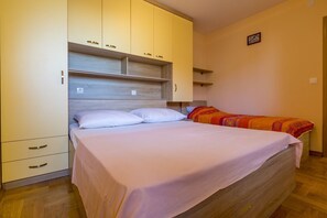 A bedroom with a bed, a wardrobe, and a small bedside table. - Modern apartment just 390 metres from the beach with stunning sea views and parking space (Dramalj)
