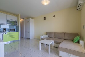 A modern living room with a beige sofa, a white coffee table, and a kitchen area with a microwave and a coffee maker. - Modern apartment just 390 metres from the beach with stunning sea views and parking space (Dramalj)
