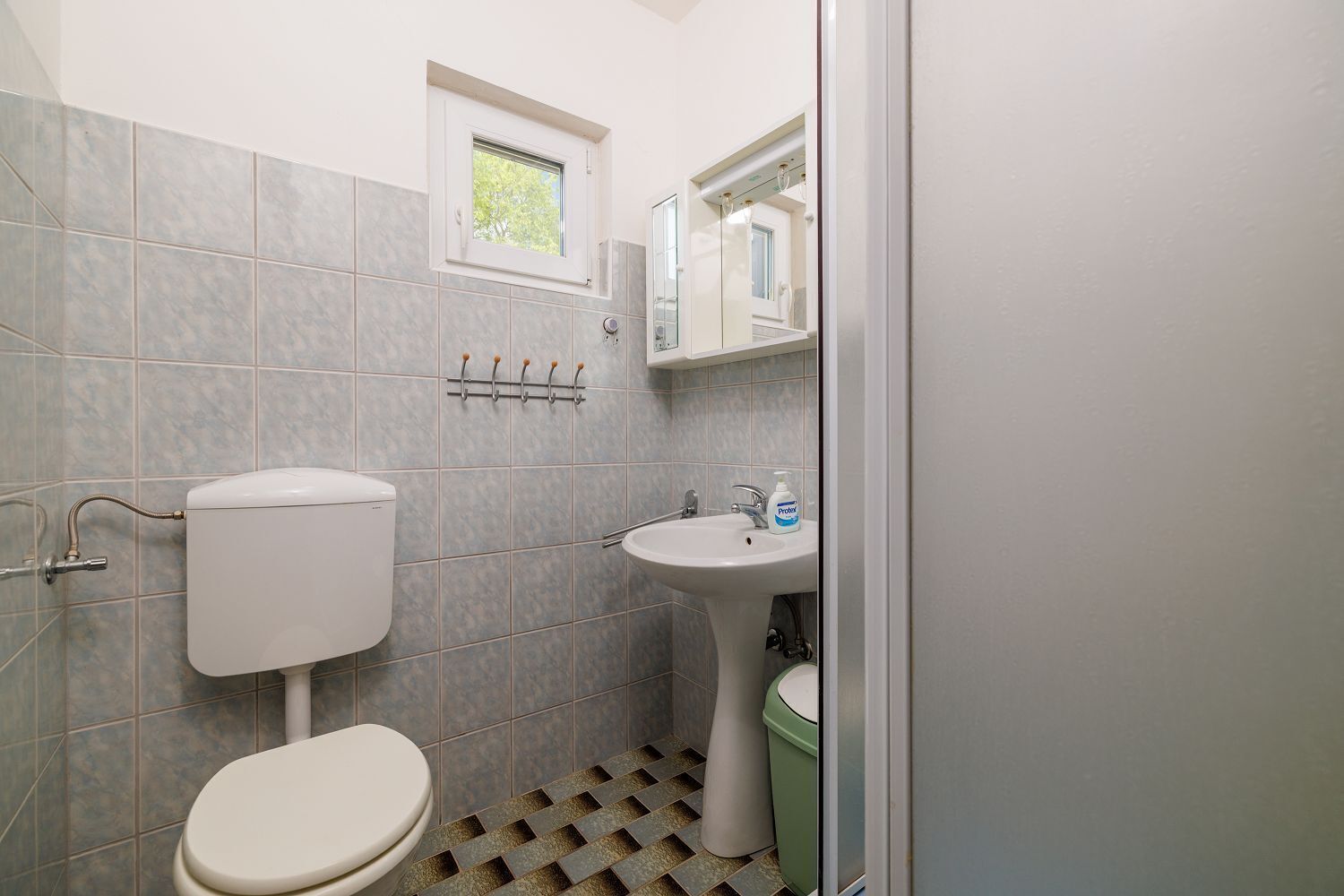 A small bathroom with a toilet, sink, and window.