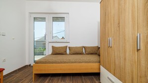 Een slaapkamer met een houten bed, een garderobe en een raam met uitzicht op gebouwen.
