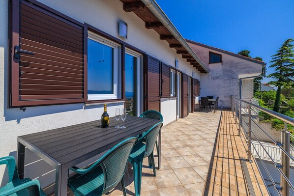 A balcony with a table set for two, a bottle of wine, and two glasses. - Picturesque studio apartment with sea view, private parking, air conditioning (Crikvenica)