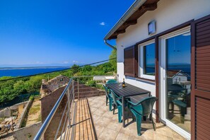A balcony with a table and chairs overlooking a scenic view of the sea. - Picturesque studio apartment with sea view, private parking, air conditioning (Crikvenica)