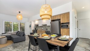Una cocina moderna con zona de comedor, que incluye una mesa de madera, sillas negras y un ventanal grande.