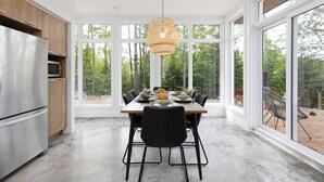 Una cocina moderna con un gran comedor, una lámpara colgante y ventanas amplias que ofrecen vistas al exterior.