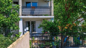 Ein zweistöckiges Gebäude mit Balkon, Topfpflanzen und einem Kiesweg.