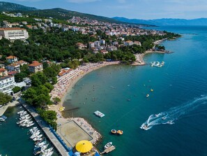 Ein Luftbild einer Küstenstadt mit Strand, Booten und einem Yachthafen.