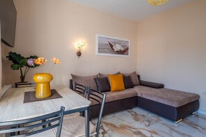 A living room with a sofa, a dining table, and chairs. There is a vase with flowers on the table. - Light-filled apartment close to the city centre with private parking (Novi Vinodolski)