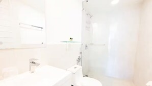 A modern bathroom with a white sink, toilet, and glass shower enclosure. - Oceanfront Serenity -V5-3E- 2 bed, 2 bath (Punta Chame)