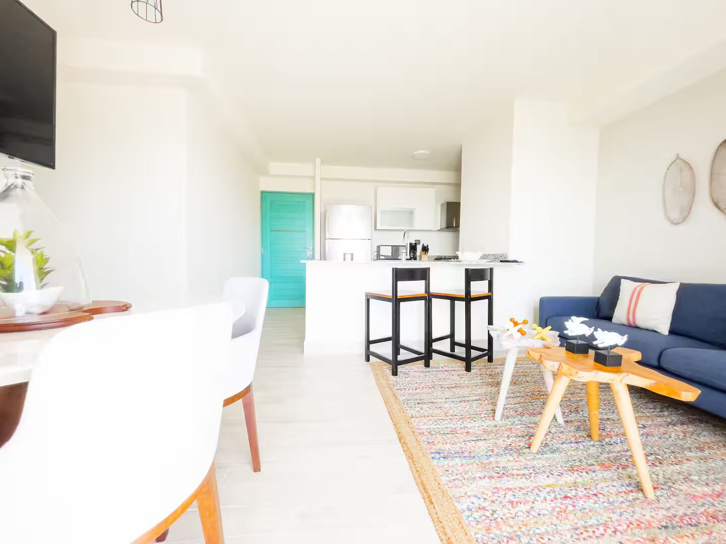 A modern living room with a sofa, a coffee table, and a dining area with a table and chairs.