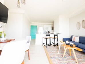 A modern living room with a blue sofa, a coffee table, and a TV mounted on the wall. - Oceanfront Serenity -V5-3E- 2 bed, 2 bath (Punta Chame)