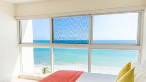 Ein Schlafzimmer mit großem Fenster und Blick auf einen Strand.